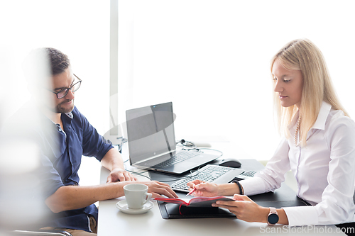 Image of Business meeting. Client consulting. Confident business woman, real estate agent, financial advisor explaining details of project or financial product to client in office.