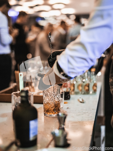 Image of Expert barman is making cocktail at business banquet event in hotel conference center. Blurred businesspeople at banquet event business meeting event in the background