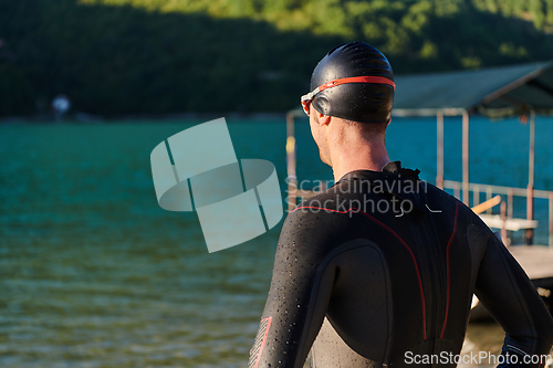 Image of Authentic triathlon athlete getting ready for swimming training on lake