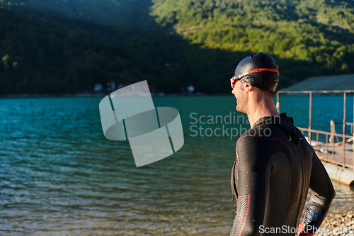 Image of Authentic triathlon athlete getting ready for swimming training on lake