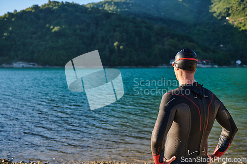 Image of Authentic triathlon athlete getting ready for swimming training on lake