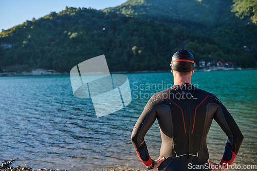 Image of Authentic triathlon athlete getting ready for swimming training on lake