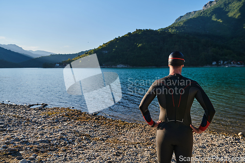 Image of Authentic triathlon athlete getting ready for swimming training on lake