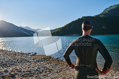 Image of Authentic triathlon athlete getting ready for swimming training on lake