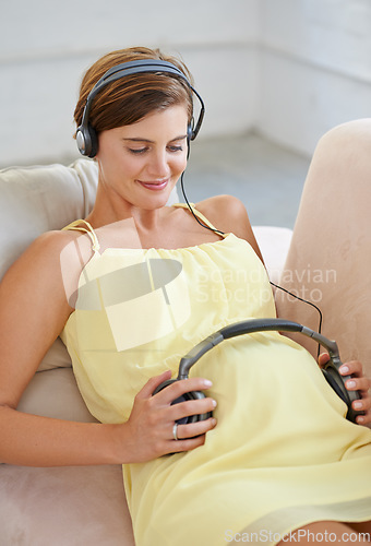 Image of Woman, song or headphones on pregnant stomach in house living room for sound, audio or childcare listening development. Relax, pregnancy or happy person and music, podcast or wellness growth support