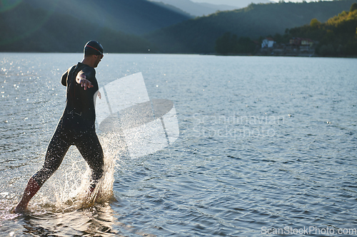 Image of Triathlon athlete starting swimming training on lake