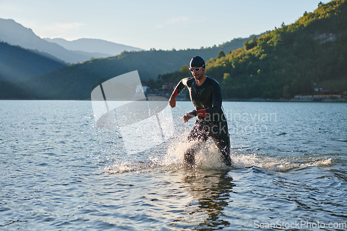 Image of Triathlon athlete starting swimming training on lake