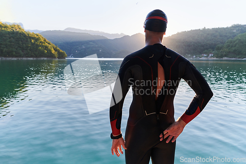 Image of Authentic triathlon athlete getting ready for swimming training on lake