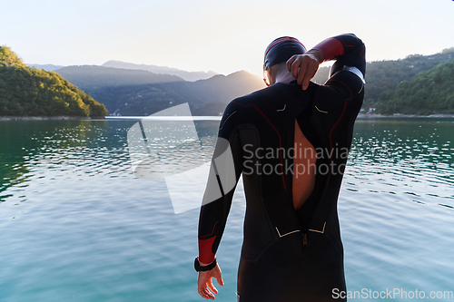 Image of Authentic triathlon athlete getting ready for swimming training on lake