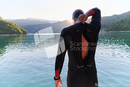 Image of Authentic triathlon athlete getting ready for swimming training on lake