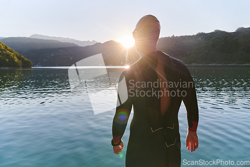 Image of Authentic triathlon athlete getting ready for swimming training on lake