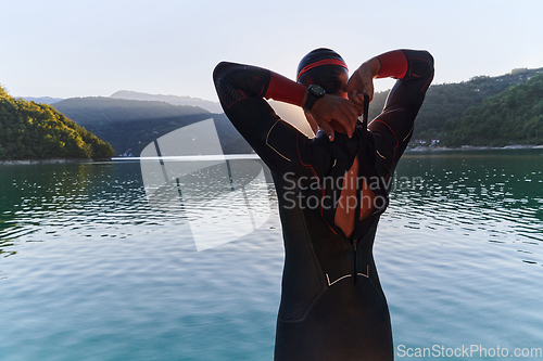 Image of Authentic triathlon athlete getting ready for swimming training on lake