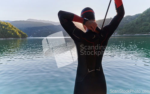 Image of Authentic triathlon athlete getting ready for swimming training on lake