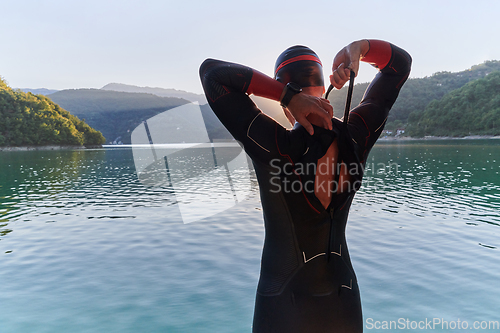 Image of Authentic triathlon athlete getting ready for swimming training on lake