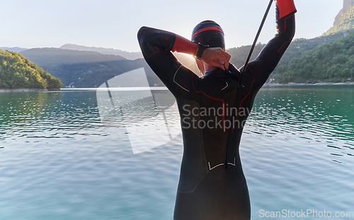 Image of Authentic triathlon athlete getting ready for swimming training on lake