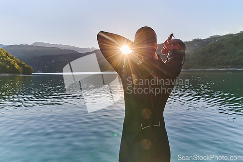 Image of Authentic triathlon athlete getting ready for swimming training on lake