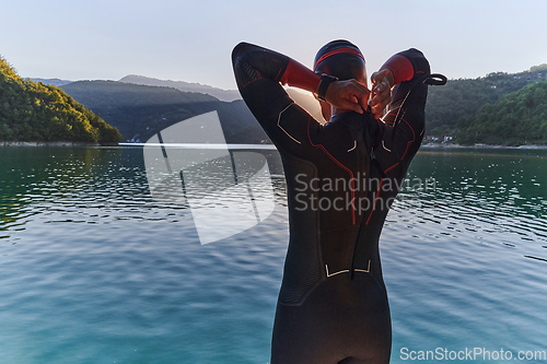 Image of Authentic triathlon athlete getting ready for swimming training on lake