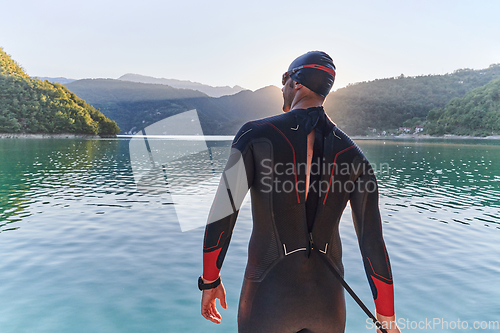 Image of Authentic triathlon athlete getting ready for swimming training on lake