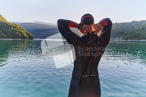 Image of Authentic triathlon athlete getting ready for swimming training on lake