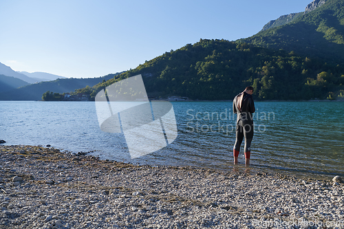 Image of Authentic triathlon athlete getting ready for swimming training on lake