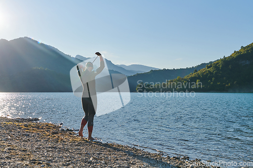 Image of Authentic triathlon athlete getting ready for swimming training on lake