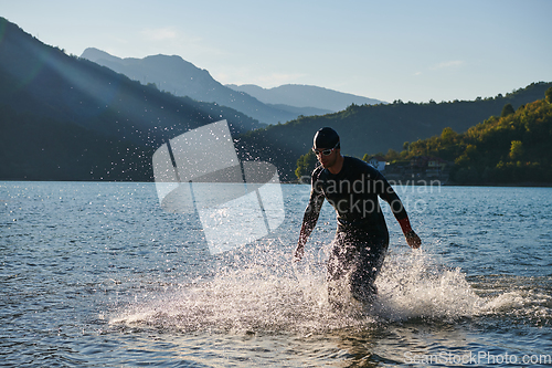 Image of Triathlon athlete starting swimming training on lake