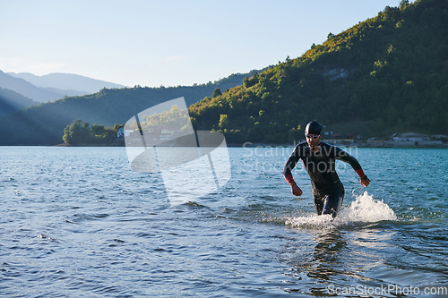 Image of Triathlon athlete starting swimming training on lake