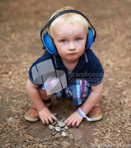 Image of Protection, boy and outdoor with headphones, portrait and relax with nature, playing and summer. Toddler, kid and childhood with noise cancelling headset, outside and sound in a park and safety