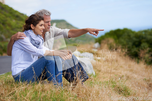 Image of Mature, couple and pointing at nature on holiday, vacation or embrace with love or support in retirement. Happy, man and woman together sightseeing on hill, mountain or relax in environment adventure