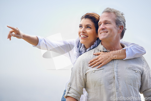 Image of Happy couple, pointing and travel together with love, happiness and cruise adventure in summer. Retirement, vacation and mature man and woman hug and sightseeing on holiday with sky mockup space