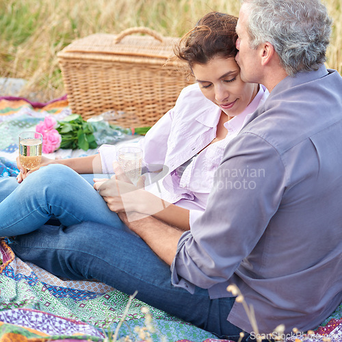 Image of Kiss, senior couple and picnic in park, grass and basket in nature for a date or celebration with love and care. Mature, woman and man in field in summer, holiday or vacation with wine or drinks