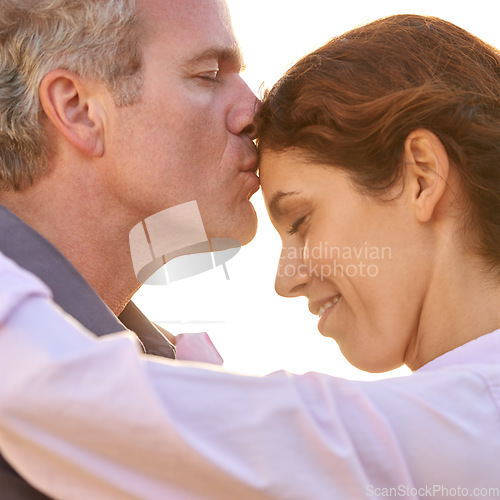 Image of Couple, forehead kiss and hug with love, respect or happiness on holiday in romance. Mature, man and woman embrace together outdoor at sunset on vacation or show affection or gratitude in marriage