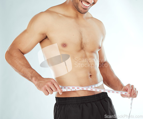 Image of Measuring tape, stomach and fitness man in studio with weight loss, progress or bmi control on white background. Body, wellness and male model with waist measurement for diet, detox or sixpack check