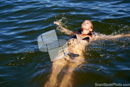 Image of Bikini, woman and floating in water at lake to relax in summer, holiday and swimming on vacation. Calm, peace and person in swimwear, fashion or body in waves of ocean or sea with freedom in nature
