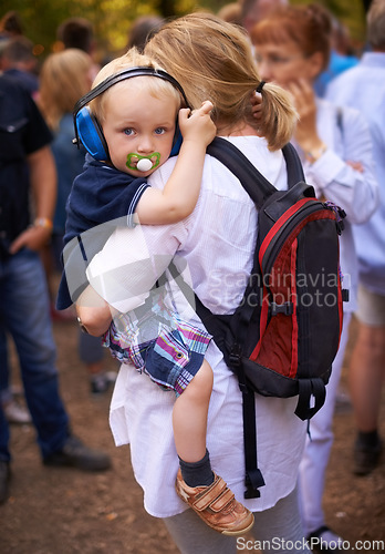 Image of Outdoor, festival and mother with baby, headphones and protection with fun, music and audio. Family, toddler and mama with kid, childhood and ear mufflers with love, embrace and bonding together