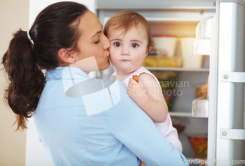 Image of Happy woman, mother and toddler with kiss in kitchen, fridge and eating of snack for hunger. Kid, little girl and hungry with fresh, organic or fruit for nutrition, vegetarian or healthy diet in home