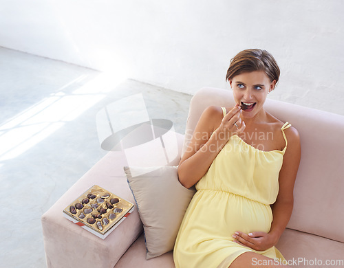 Image of Pregnant woman, eating chocolate and relax in home, alone and happy for delicious pregnancy craving. Good mood, comfort food and candy dessert for maternity, snack and sweet tooth satisfaction
