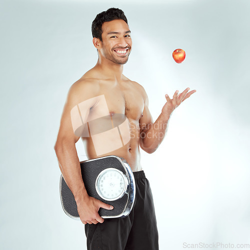 Image of Wellness, scale and happy man portrait with apple throw in studio for health, diet or Weight loss motivation on white background. Nutrition, detox or face of Japanese model fruit, balance or progress
