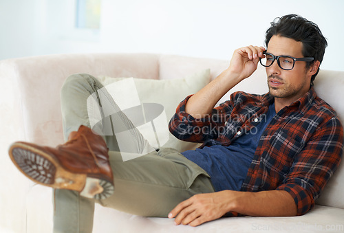 Image of Home, sofa and man relax with glasses for eyesight and headache from problem with vision in living room. Hipster, person and thinking on couch in apartment with spectacles for farsighted healthcare