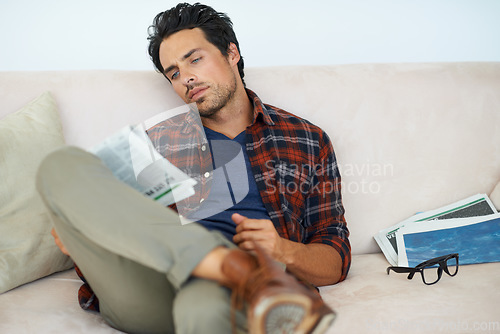 Image of Man, reading and relax with newspaper on couch in home, living room and learning about event from media. Calm, weekend and person with news, paper or magazine on sofa in apartment for information