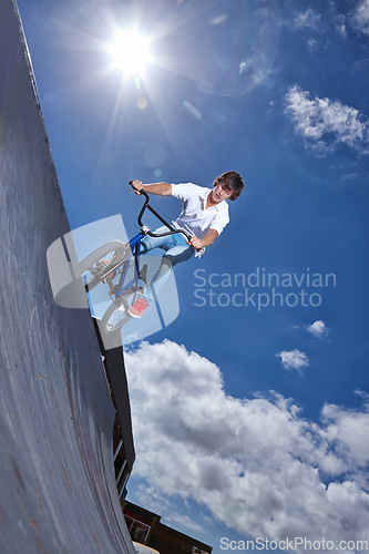 Image of Ride, bike and teen on ramp for sport performance, jump or training for event at park with blue sky mockup. Bicycle, stunt or kid balance on edge of board in trick for cycling competition challenge