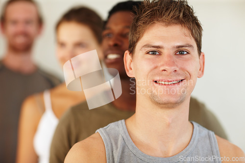 Image of Portrait, smile or fitness and man with a group of people in a studio for health, wellness or mindfulness. Exercise, workout and pilates with a happy young person in gym class for holistic training