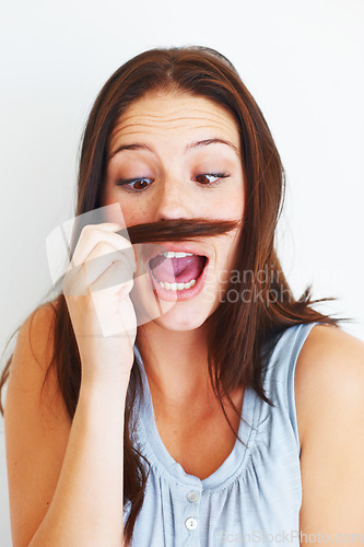 Image of Woman, silly and playing with hair mustache by white background, hairstyle and funny joke in studio. Female model person, comic and comedy for haircare or goofy, beauty treatment and cosmetology