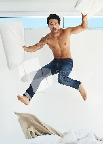 Image of Portrait, bed and jump with a shirtless man in his home for freedom, energy or fun on a weekend morning. Bedroom, excitement and the body of a masculine young person leaping in his apartment