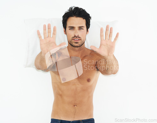 Image of Portrait, stop and palms of a man on his bed in studio isolated on a white background for rejection. Face, hand gesture and pillow with the body of a shirtless young model in the bedroom of his home