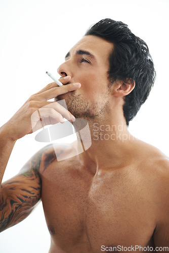 Image of Man, cigarette and smoking for addiction or drag of tobacco against a white studio background. Face of handsome or attractive male person, model or smoker addict in relax and enjoying stress relief
