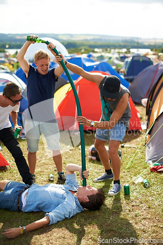 Image of Man, friends and beer pipe at outdoor festival, camp or party together with alcohol on green grass or field. Group of people pouring drink down tube in nature by tents at event or carnival outside