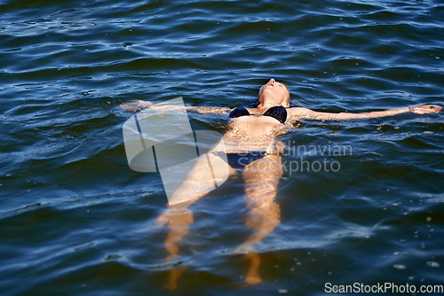 Image of Ocean, water and woman floating in bikini with peace and freedom in summer, holiday or vacation. Person, relax and calm swimming in sea, lake or pool with swimwear, costume and waves offshore