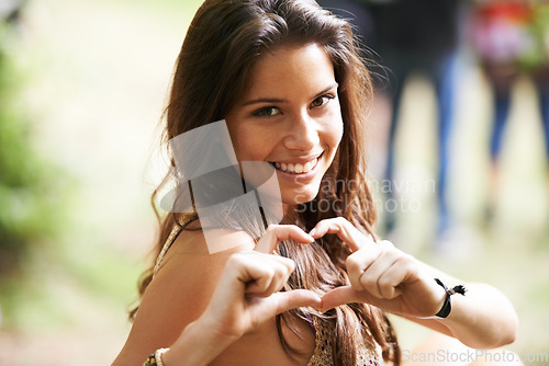 Image of Happy woman, portrait and heart hands at outdoor music festival with crowd for love, care and support. Face of female person smile with like emoji, romance or symbol for unity or community at concert