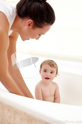 Image of Baby in bathtub with mom, water and clean fun in home for skincare, wellness and hygiene. Bubble bath, soap and happy child in bathroom with cute face, care and washing body of dirt, germs and mother